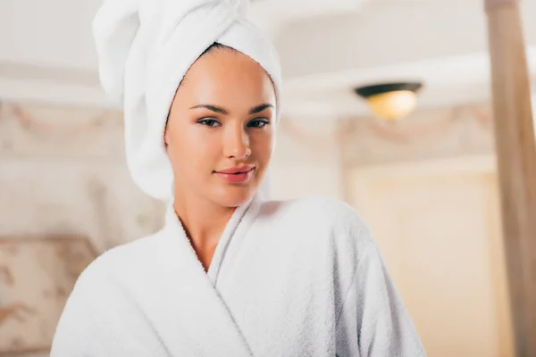 Mujer sonriente en albornoz de felpa con toalla en la cabeza en el centro de spa - foto de stock