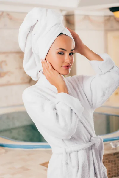 Jovem sorrindo mulher relaxante com toalha na cabeça no centro de spa com piscina — Fotografia de Stock