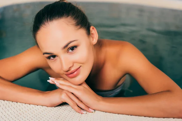 Frau entspannt sich im Schwimmbad und blickt in Kamera — Stockfoto