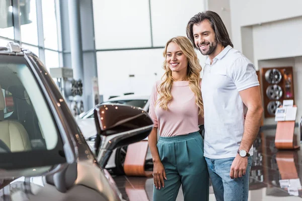 Fröhliches Paar wählt Auto im Autohaus-Salon — Stockfoto