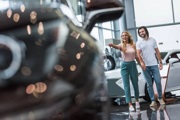 Jeune couple choisissant l'automobile au salon de concession — Photo de stock