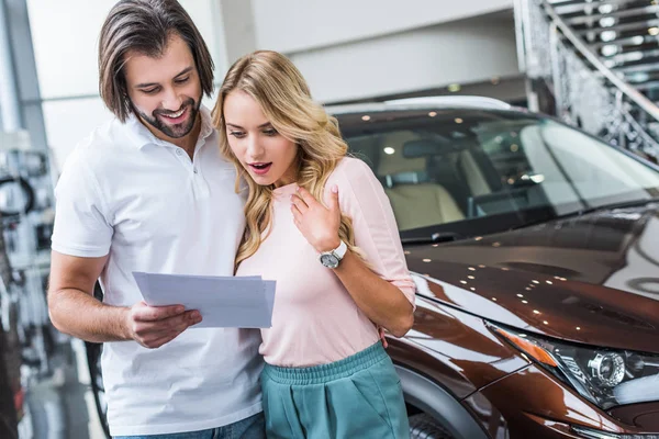Portrait of couple with catalog choosing car at dealership salon — Stock Photo