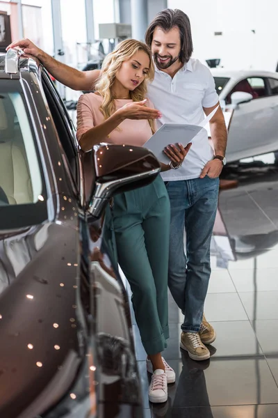 Couple avec catalogue acheter une voiture chez le concessionnaire salon — Photo de stock