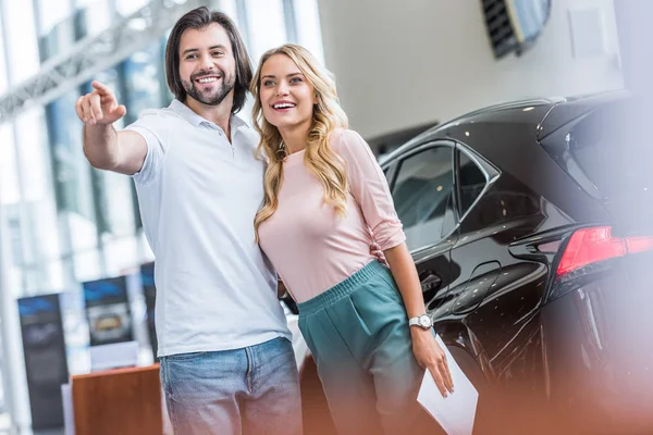 Sorrindo casal com catálogo de compra de carro no salão de concessionárias — Fotografia de Stock