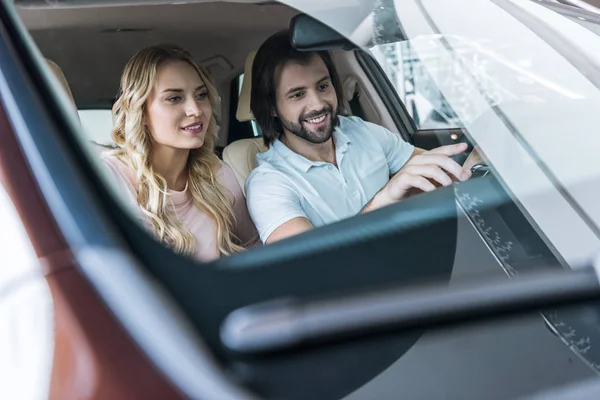 Young couple sitting in car at dealership salon — Stock Photo