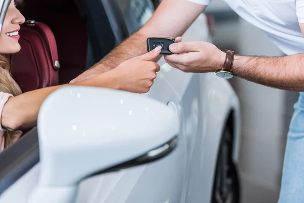 Cropped shot of man giving car key to woman at dealership salon — Stock Photo