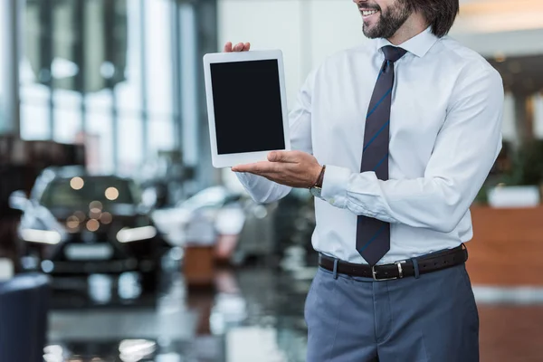 Обрізаний знімок продавця чоловіків у формальному одязі, що показує планшет з порожнім екраном у дилерському салоні — стокове фото