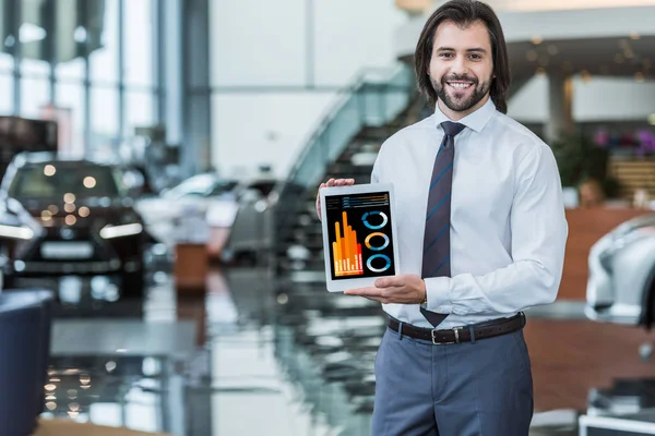 Portrait of cheerful dealership salon seller in formal wear showing tablet with infographic in hands — Stock Photo