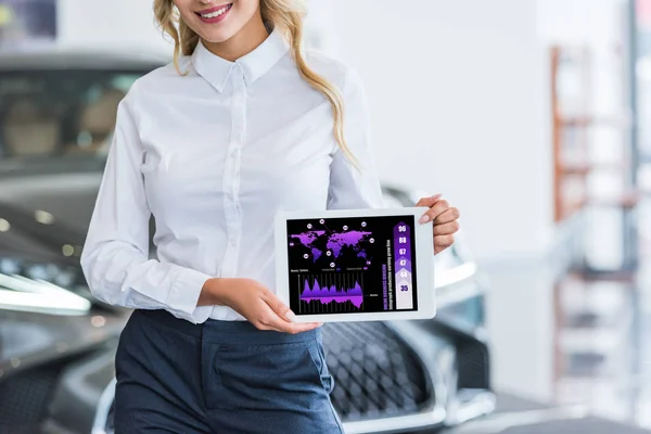 Teilansicht Verkäuferin zeigt Tablet mit Infografik in der Hand im Autohaus-Salon — Stockfoto