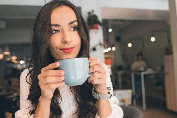 Selective focus of young attractive woman drinking coffee at table in cafe — Stock Photo