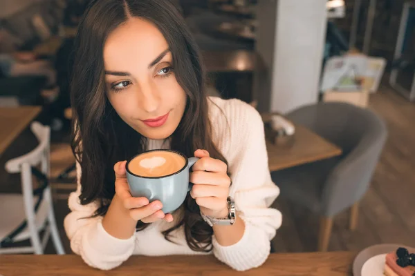 Високий кут зору молодої привабливої жінки, що п'є каву за столом у кафе — стокове фото
