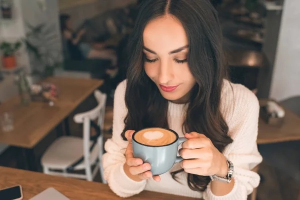 Vue grand angle de jeune femme attrayante buvant du café à table dans un café — Photo de stock