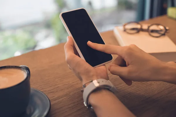 Imagen recortada de la mujer tomando la foto de la taza de café en el teléfono inteligente en la mesa en la cafetería - foto de stock
