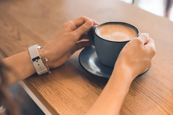 Abgeschnittenes Bild einer Frau, die mit Kaffeetasse am Tisch im Café sitzt — Stockfoto