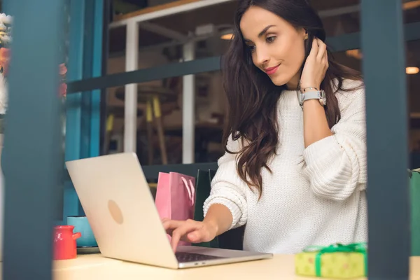 Beautiful female freelancer working with laptop at table in cafe — Stock Photo