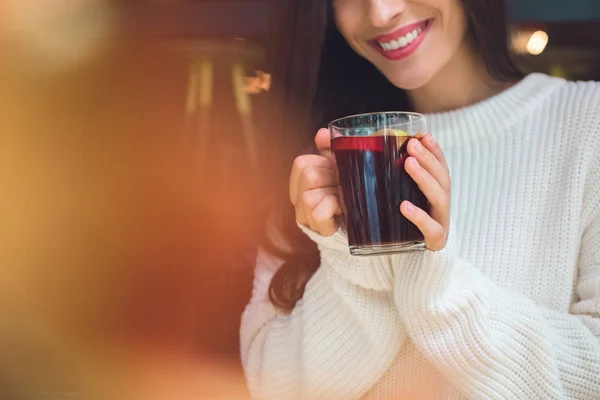 Imagem recortada de mulher sorridente segurando xícara de vinho quente à mesa no café — Fotografia de Stock