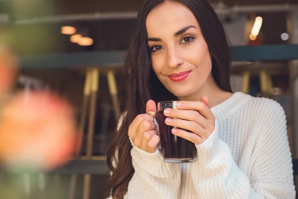 Ritratto di giovane donna che tiene in mano una tazza di vin brulè a tavola nel caffè — Foto stock