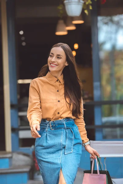 Fröhliche, stylische junge Frau läuft mit Einkaufstüten durch die City — Stockfoto