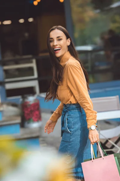 Сміється стильна молода жінка, що йде з сумками на міській вулиці — стокове фото