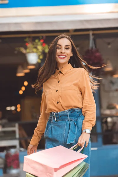 Jeune acheteur élégant femme heureuse marchant avec des sacs à provisions à la rue de la ville — Photo de stock