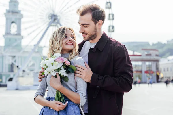 Fidanzato abbracciare fidanzata con bouquet in città — Foto stock