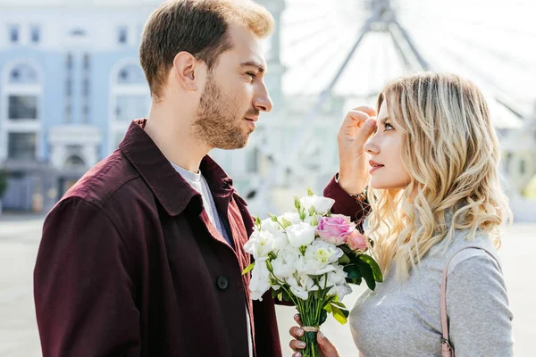 Novio tocando novia pelo y ellos mirando el uno al otro en la ciudad - foto de stock