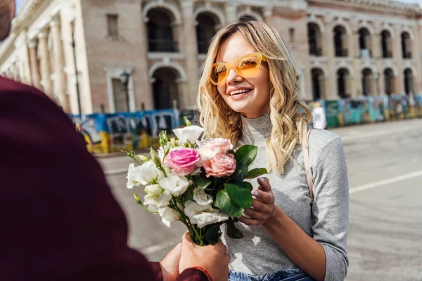 Imagen recortada de novio presentando ramo de rosas a novia en la calle en la ciudad - foto de stock