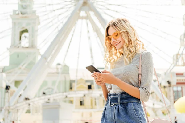 Schöne lächelnde Frau im herbstlichen Outfit mit Smartphone in der Nähe des Rades in der Stadt — Stockfoto