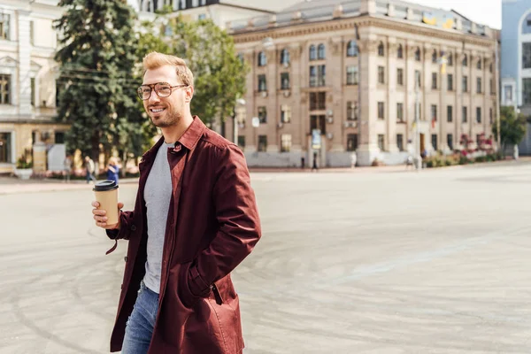 Bel homme en tenue d'automne marche avec tasse de café jetable en ville — Photo de stock