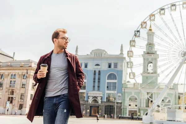 Schöner Mann im herbstlichen Outfit spaziert mit Einweg-Kaffeetasse in der Nähe des Beobachtungsrads — Stockfoto