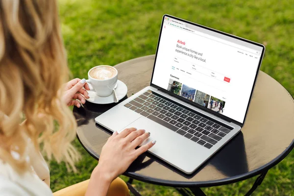 Abgeschnittenes Bild einer Frau mit Laptop und geladener Airbnb-Seite auf Tisch im Garten — Stockfoto