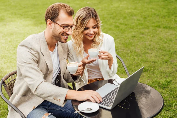 Pareja en traje de otoño trabajando con el ordenador portátil y beber café en la cafetería - foto de stock