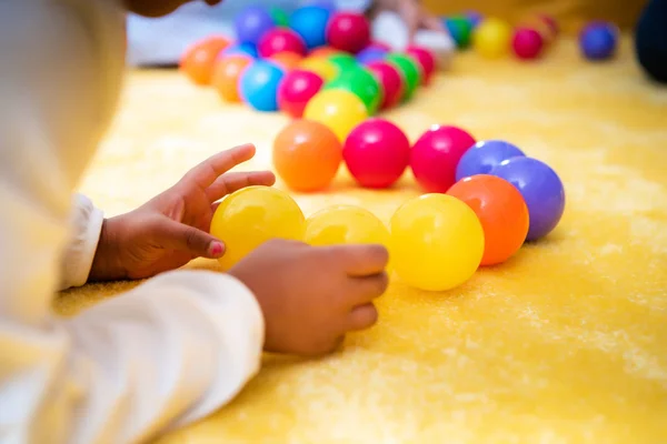 Imagen recortada de niño afroamericano jugando con bolas de colores en el jardín de infantes - foto de stock