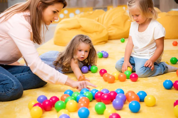 Erzieher zeigt Kindern im Kindergarten auf farbige Bälle — Stockfoto