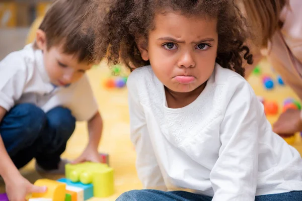 Unzufriedene afrikanisch-amerikanische Kinder, die im Kindergarten grimmig in die Kamera schauen — Stockfoto