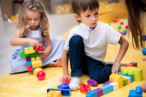 Niños y niñas jugando con el constructor en el jardín de infantes - foto de stock