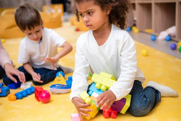 Bouleversé afro-américain enfant prendre des pièces de constructeur à la maternelle — Photo de stock