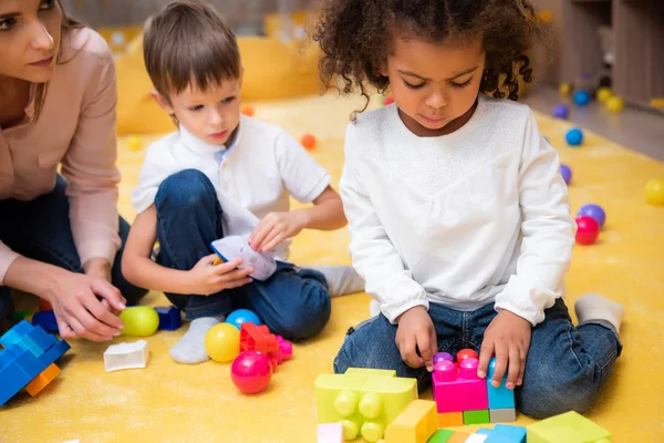 Upset african american child playing with colored constructor in kindergarten — Stock Photo