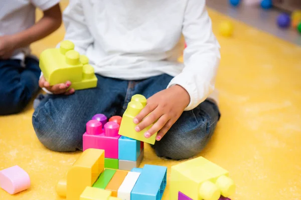 Geschnittenes Bild eines afrikanisch-amerikanischen Kindes, das im Kindergarten mit einem Bauarbeiter spielt — Stockfoto