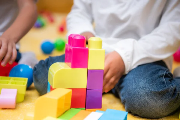 Imagen recortada de niño afroamericano jugando con constructor de plástico en el jardín de infantes - foto de stock