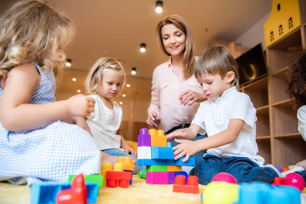 Livello superficiale di educatore e bambini che giocano con il costruttore nella scuola materna — Foto stock