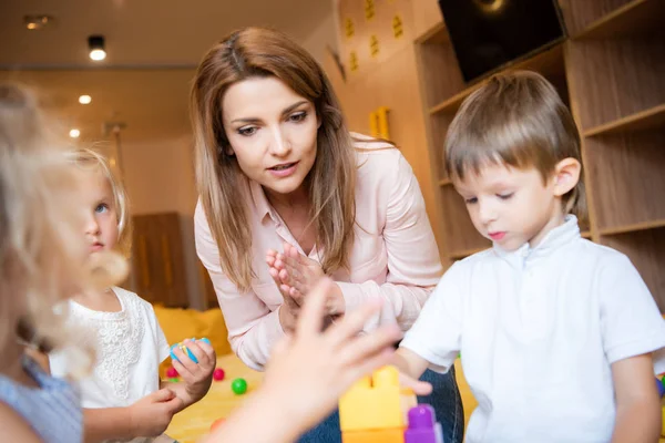 Foyer sélectif de l'éducateur et des enfants jouant avec le constructeur éducatif à la maternelle — Photo de stock