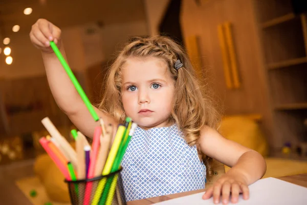 Criança adorável tomando caneta de ponta de feltro verde para desenhar no jardim de infância — Fotografia de Stock