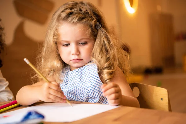 Adorable caucasian kid drawing in kindergarten — Stock Photo