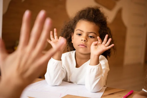 Imagen recortada del educador enseñando números de niños afroamericanos en el jardín de infantes - foto de stock