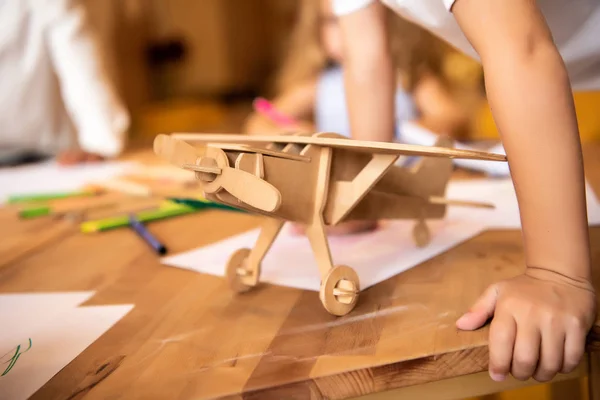 Children drawing in kindergarten, wooden plane on foreground — Stock Photo