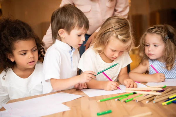 Abgeschnittenes Bild eines Erziehers, der neben multikulturellen Kindern steht, die im Kindergarten zeichnen — Stockfoto