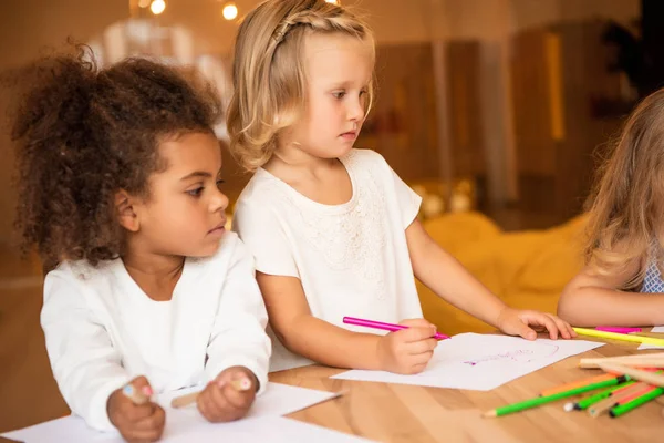 Adorable multicultural friends drawing together in kindergarten — Stock Photo