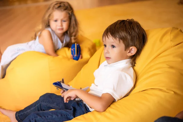 Crying kid with boat toy looking at boy with plane toy in kindergarten — Stock Photo