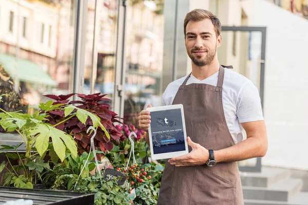 Schöner Blumenhändler, der Tablette mit geladener Tumblr-Seite in der Nähe von Blumenladen hält — Stockfoto